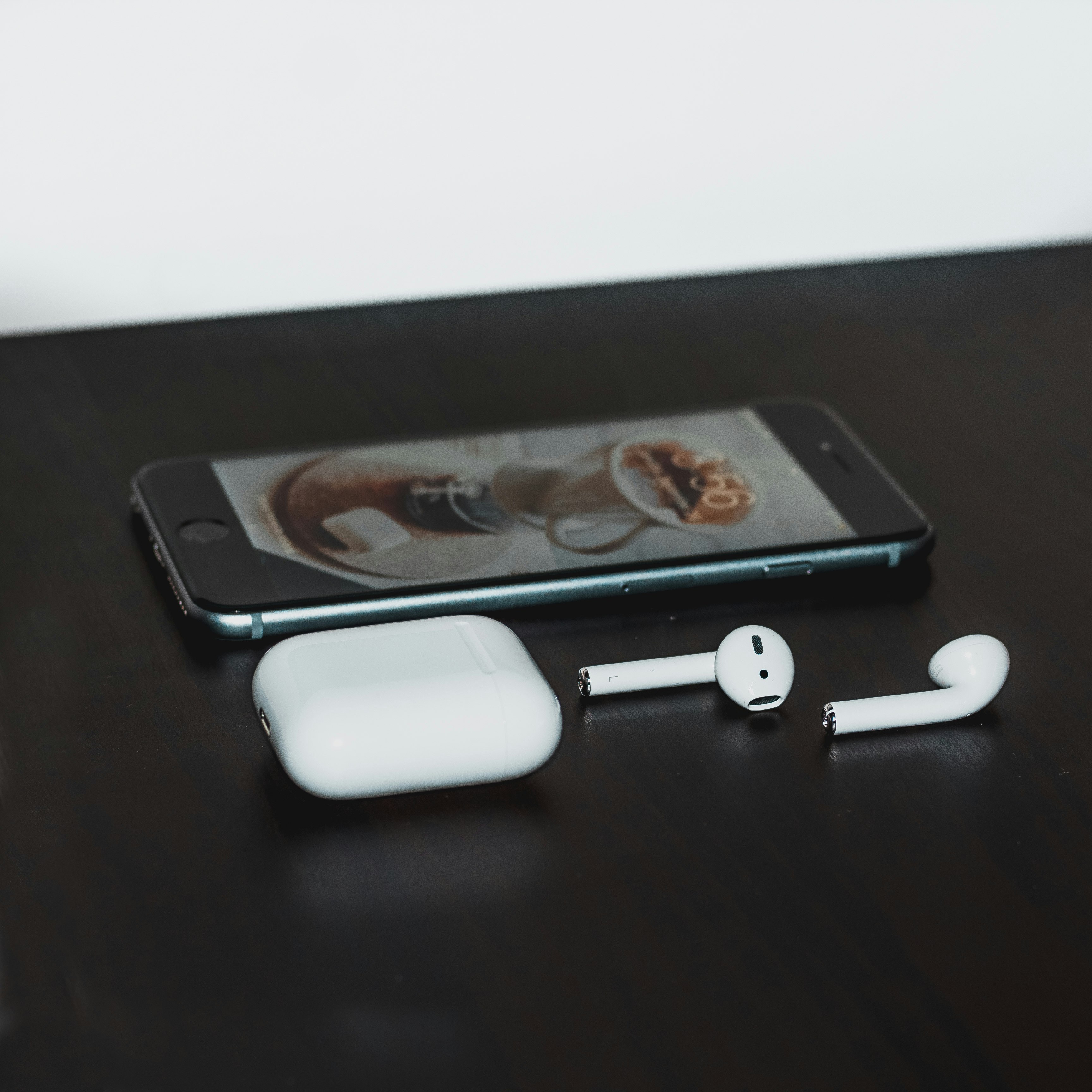 space gray iPhone 6 and Apple AirPods with case on black wooden table